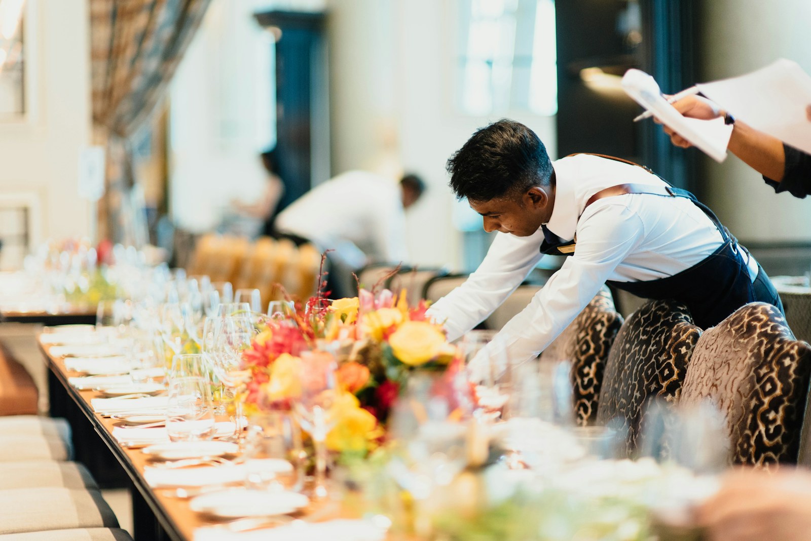 Eine Servicekraft deckt eine festliche Tafel für eine Veranstaltung